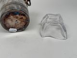 a glass jar with a metal lid next to a small glass container