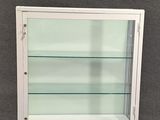 une vitrine blanche surmontée d'étagères en verre