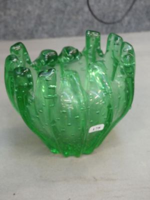 a green glass bowl sitting on a table next to a wall