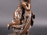 an antique bronze statue of a woman sitting on a chair