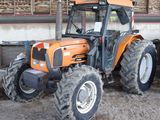 an orange tractor that is parked in the dirt