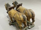two figurines of two horses pulling a sleigh