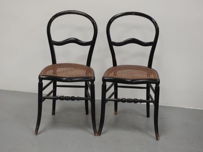 deux chaises noires à assise en osier dans une pièce blanche