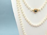 a close up of a necklace with pearls on a mannequin