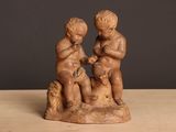 une petite statue représentant deux enfants assis sur un rocher