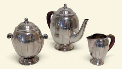 three silver teapots and a pitcher on a table