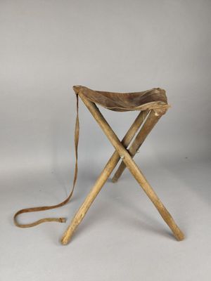 un petit tabouret en bois avec une assise en cuir, sur fond blanc