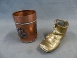 a gold boot and a copper cup on a table