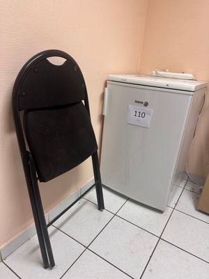 une chaise noire et un réfrigérateur blanc dans une petite pièce