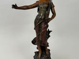 an antique bronze statue of a woman holding a bird on top of a wooden base