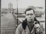 photographie en noir et blanc d'un homme fumant la pipe sur une jetée