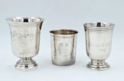 trois tasses en argent posées l'une à côté de l'autre sur une surface blanche