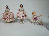 five figurines of women dressed in pink dresses