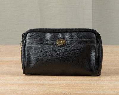a black leather toilet bag sitting on top of a wooden table