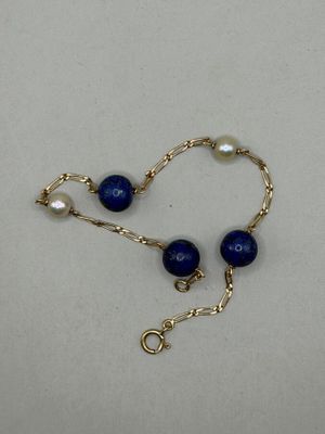 un gros plan d'un collier de perles bleues posé sur une surface blanche
