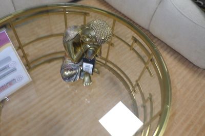 une table basse dorée avec un plateau en verre, sur laquelle est posée une figurine