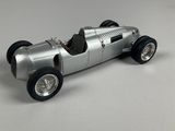a silver model of a racing car on a white surface