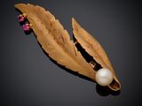 a close up of a broochle with a pearl and gold leaf