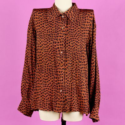une chemise à imprimé léopard marron et noir sur un mannequin de boutique