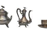 three silver teapots and a cup on a white background