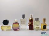 plusieurs types différents de flacons de parfum alignés sur une surface blanche