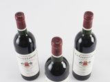 three bottles of red wine sitting next to each other on a white surface