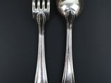 two silver spoons and a fork on a black table