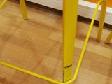 a yellow bar stool sitting on a hard wood floor