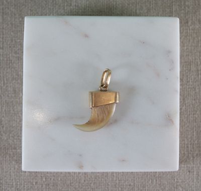 une photo d'un pendentif plaqué or posé sur une surface en marbre