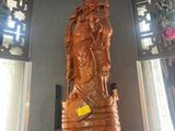 une statue en bois représentant une personne, posée sur une étagère dans un coin de la pièce