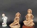 three figurines of a woman and a child on a rock