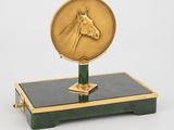 une image représentant une horloge dorée et verte ornée d'une tête de cheval