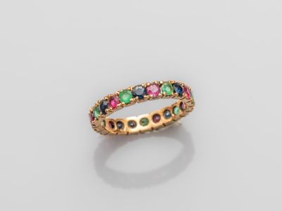 une bague en or ornée de pierres multicolores sur fond blanc
