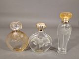 three glass perfume bottles sitting next to each other on a table