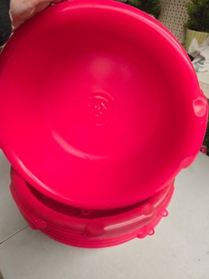 une personne tenant un bol en plastique rouge posé sur une table