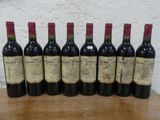 six bouteilles de vin sont alignées sur une table en bois
