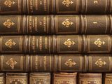 many old books stacked on top of each other on a shelf