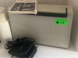 un petit réfrigérateur posé sur un plan de travail, à côté d'un téléphone