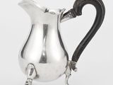 une cruche ancienne en argent avec une anse noire sur fond blanc
