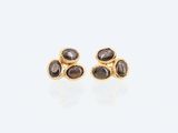 une paire de boucles d'oreilles en or ornées de pierres noires sur fond blanc
