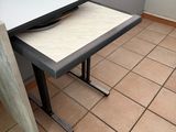 a white table with a black top sitting on a tiled floor
