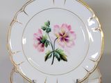 three plates with flowers painted on them on a table