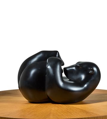 une sculpture noire posée sur une table en bois