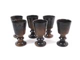 six black glass goblets sitting next to each other on a white surface