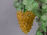 a green vase with a bunch of yellow grapes on it