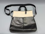 black and white leather handbag with zippers on a grey background