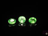 a group of three green gems sitting on top of a black surface