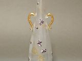 a glass vase that has a gold handle on it