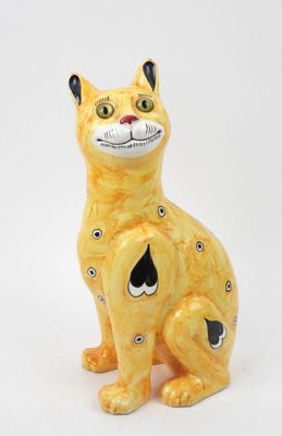 une figurine de chat jaune posée sur une surface blanche