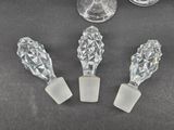 three crystal wine glasses and a glass stopper on a table